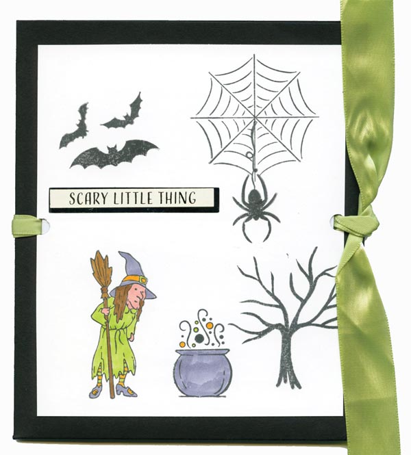 A card with a witch holding a broom looking over a cauldron with a tree, bats and spider in the background